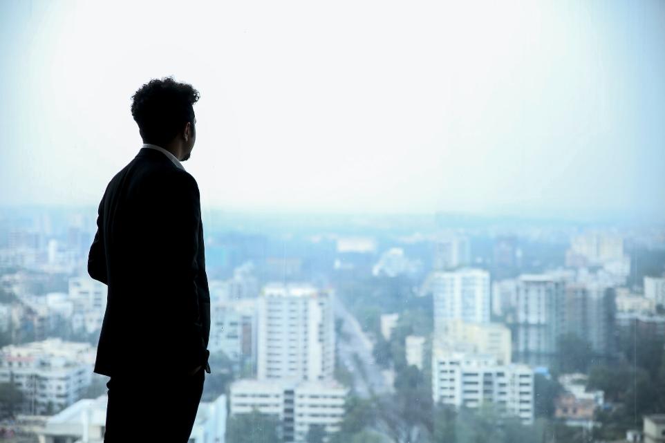 man in black suit standing on top of building looking at city buildings during daytime